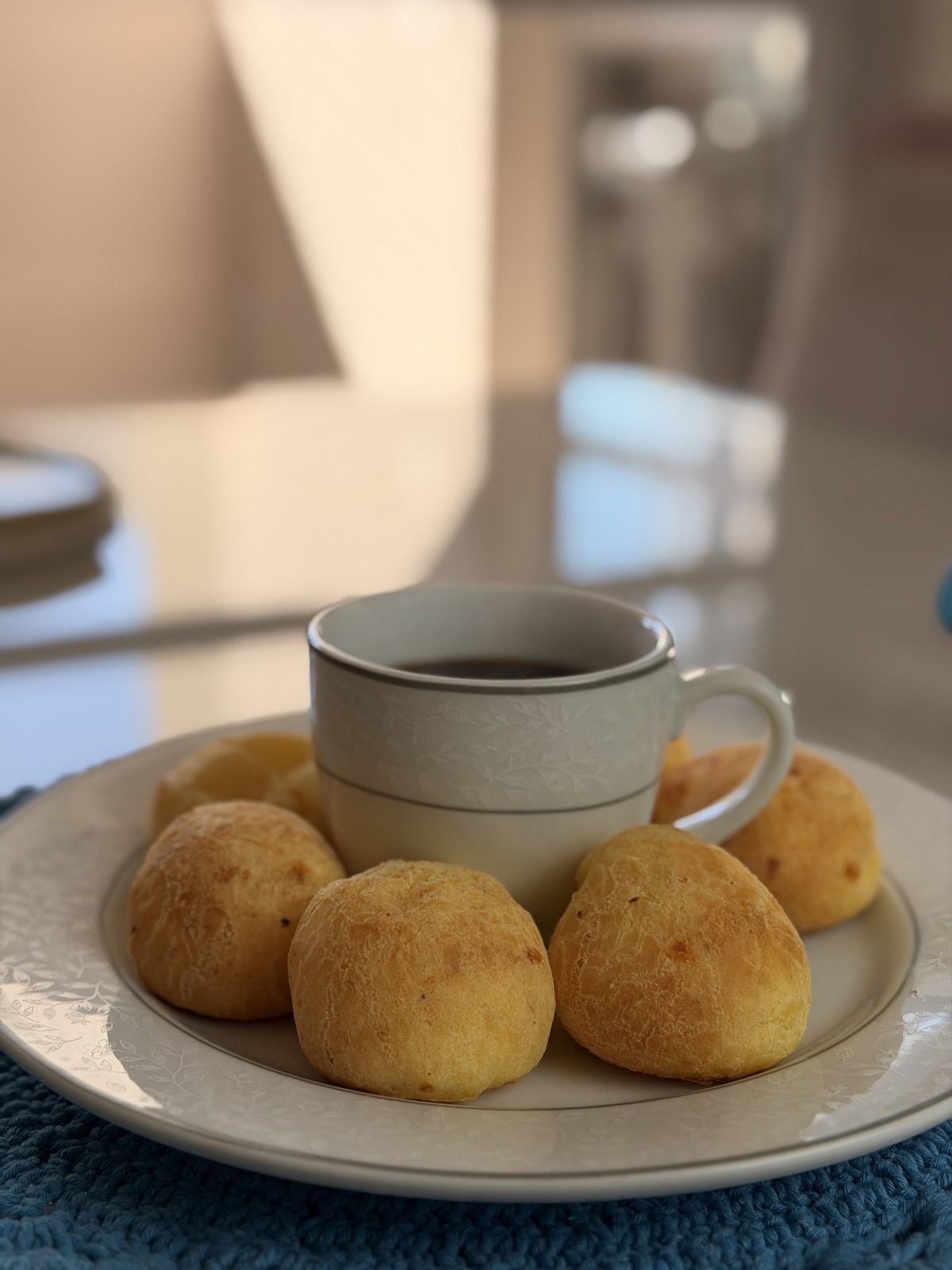 Pães de queijo quentes servidos em volta de uma xícara de café
