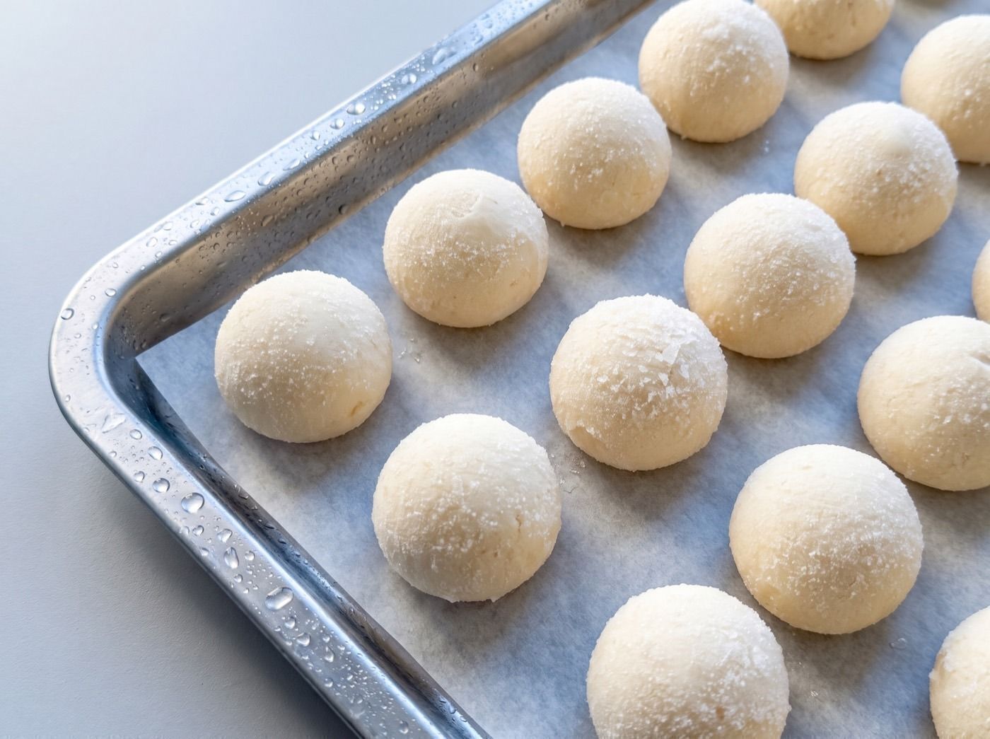 Pães de queijo crus e congelados numa assadeira